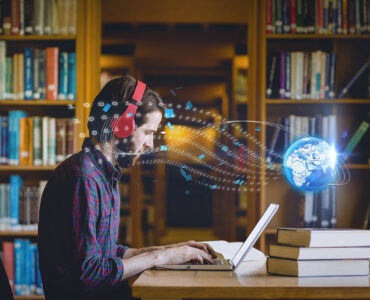 Composition of digital globe over male student using laptop in library. global education, digital interface, technology and networking concept digitally generated image.