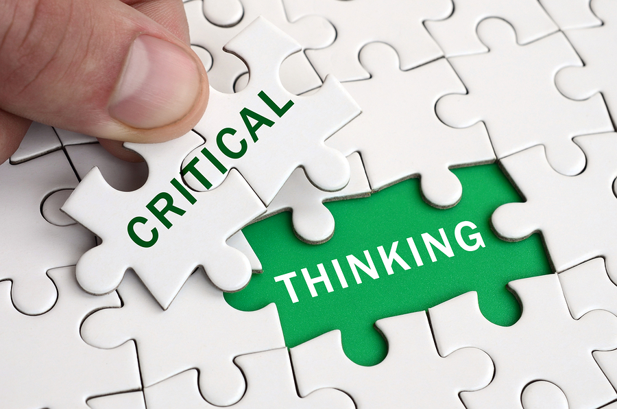 A hand placing a puzzle piece with the word CRITICAL into a gap revealing the word THINKING