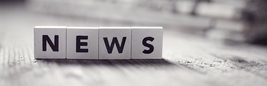 Four white wooden blocks spelling out the word NEWS in black capital letters on a wooden surface.