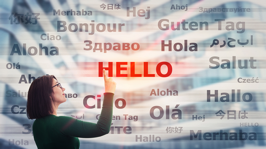 A woman points to the word "HELLO" highlighted in red among many other "hello" translations.