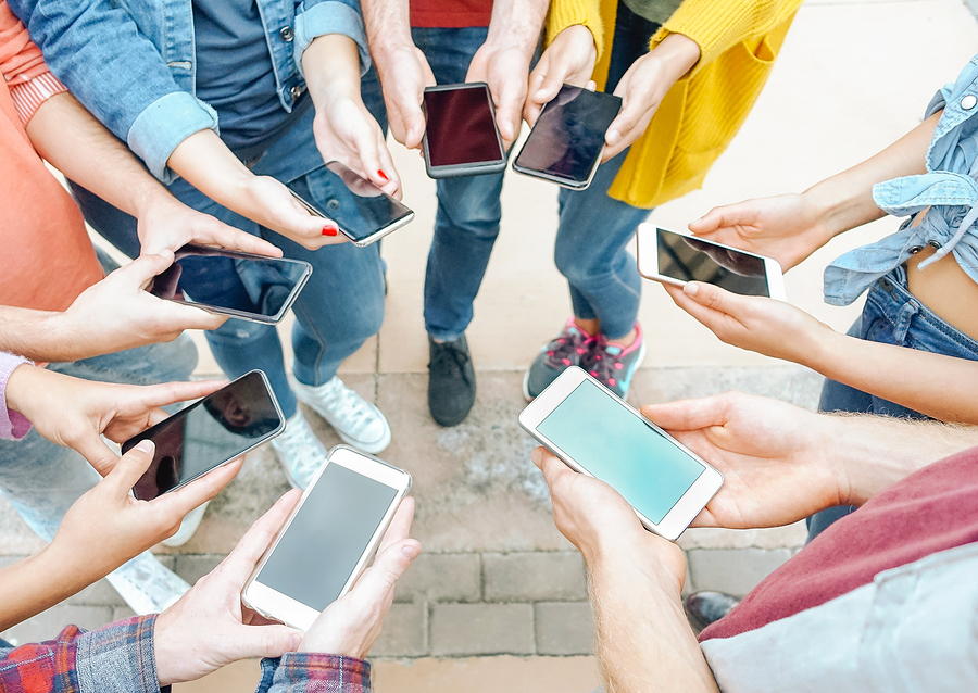A group of people stand in a circle, holding up their smartphones with blank screens.