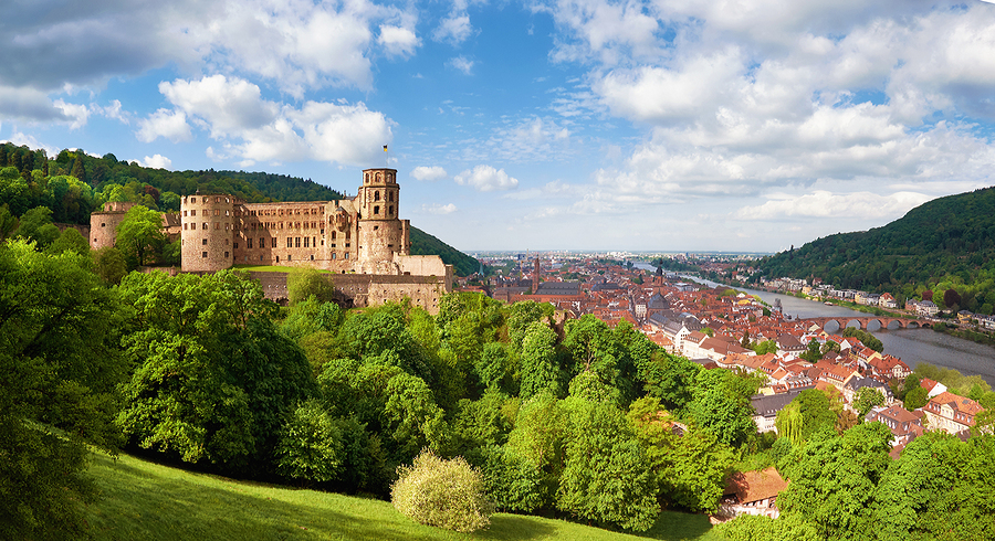 Heidelberg Castle on a hill overlooking the city and Neckar River, surrounded by green trees