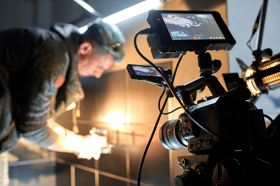 A person filming with a professional video camera, with a monitor showing the shot.