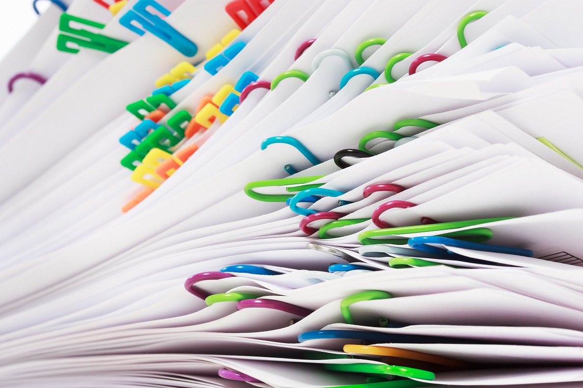 Close-up of a stack of white papers, each section separated by colourful plastic paper clips