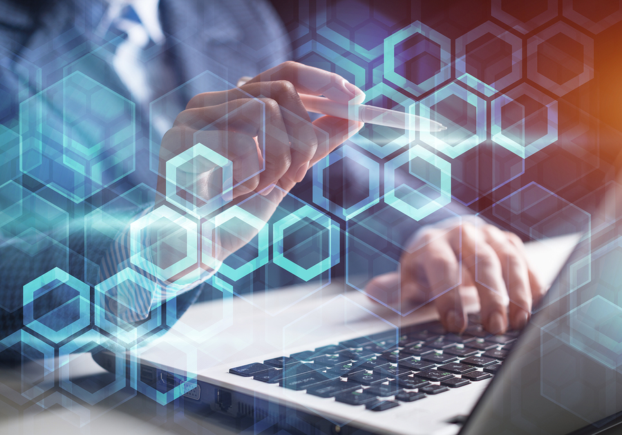 Hands interacting with a laptop and a stylus, overlaid with a pattern of glowing blue hexagons.