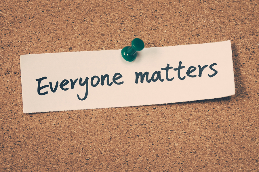 A white piece of paper with the handwritten words "Everyone matters" pinned to a cork board.