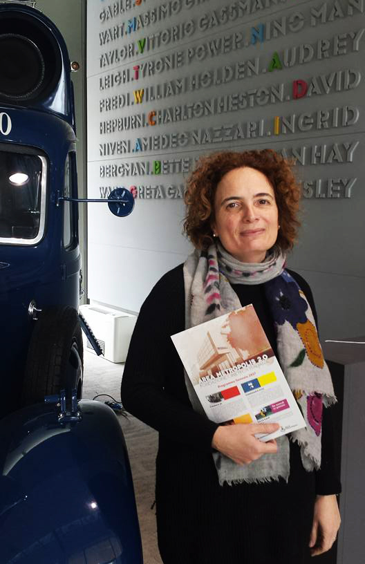 Silvia Pareti holding a brochure, standing in front of a wall with names of film stars