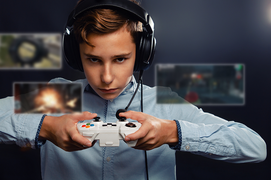 A boy wearing headphones and a microphone headset, holding a white video game controller.