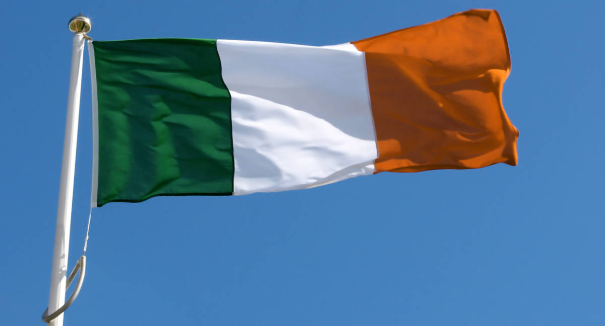 The national flag of Ireland, with vertical stripes of green, white, and orange, against a blue sky.