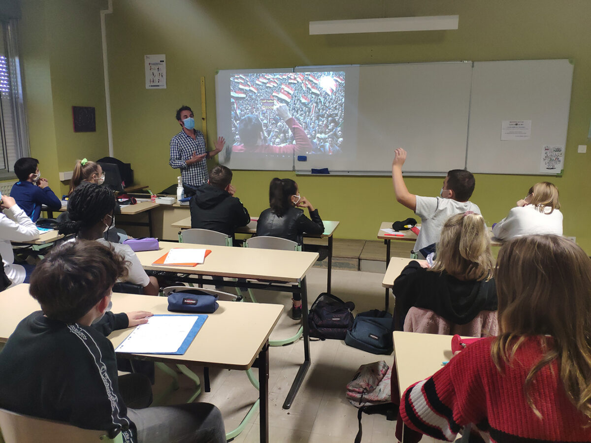 Arnaud Finistre, a photoreporter, presents an image to students in a classroom, one student raises a hand.