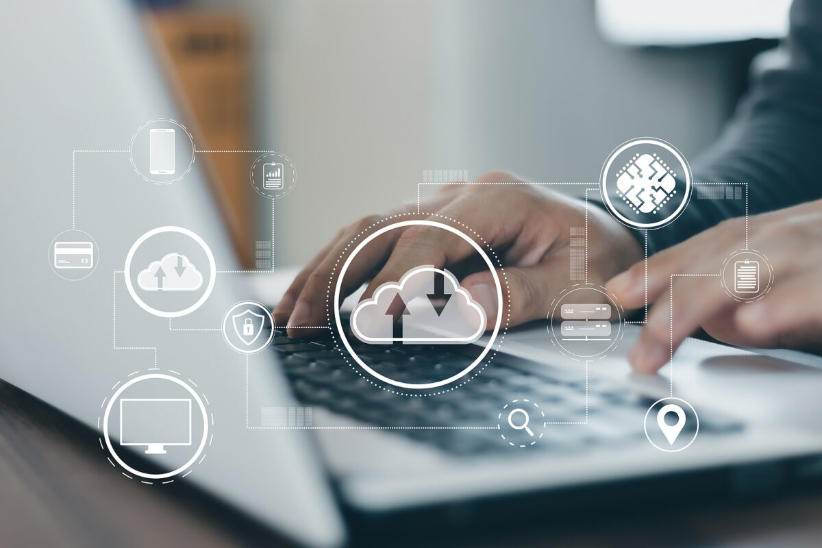 Hands typing on a laptop keyboard, surrounded by a network of cloud computing and data icons.