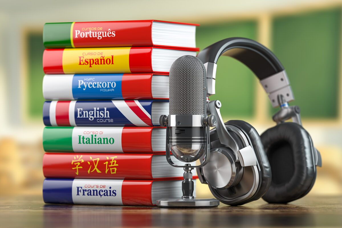 Stack of language course books (Portuguese, Spanish, Russian, English, Italian, Chinese, French) with microphone and