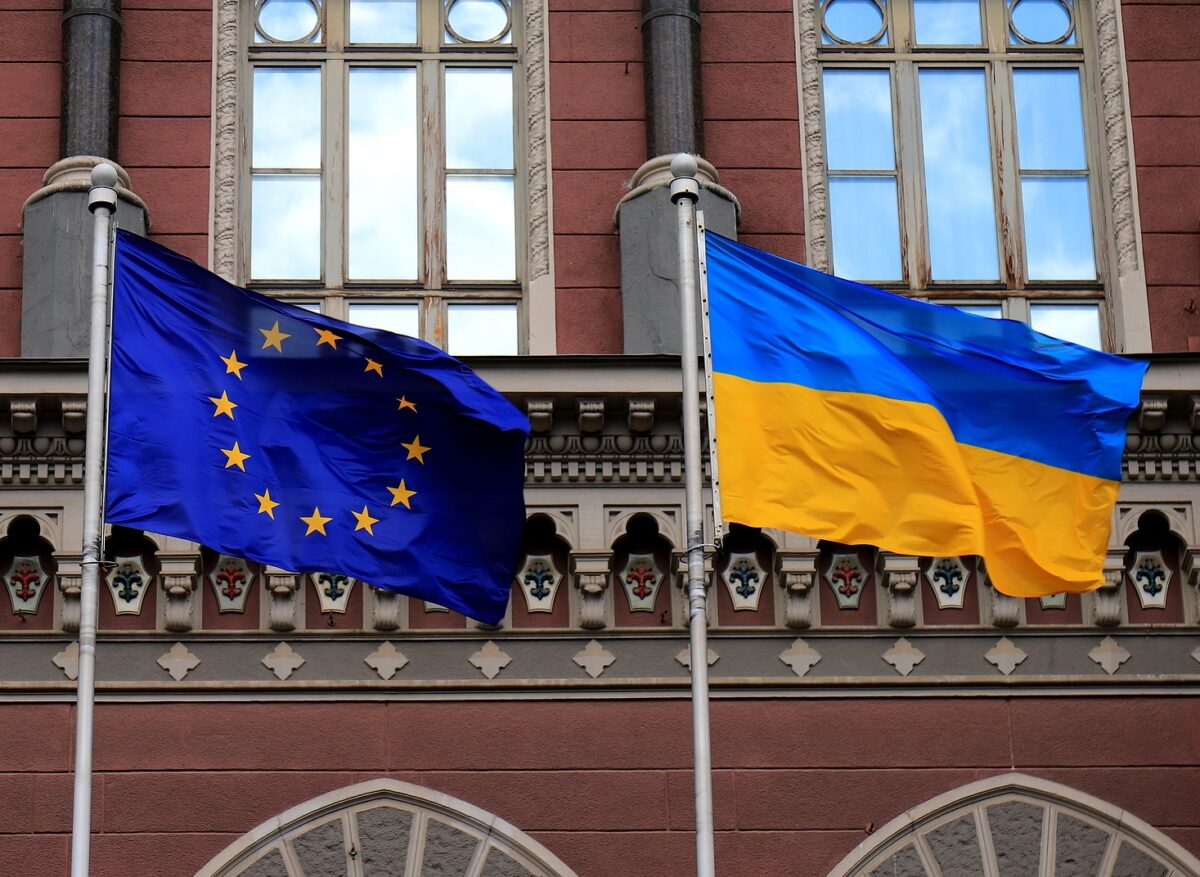 The flags of Ukraine and the European Union flying side by side in front of a building.