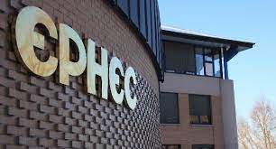 The golden letters of the EPHEC logo on a brick wall, with the building in the background