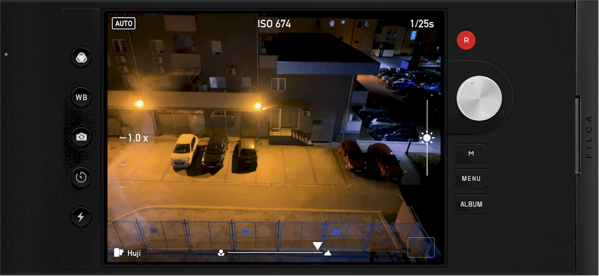 Screenshot of a smartphone camera app interface, showing a night scene with cars in a car park.