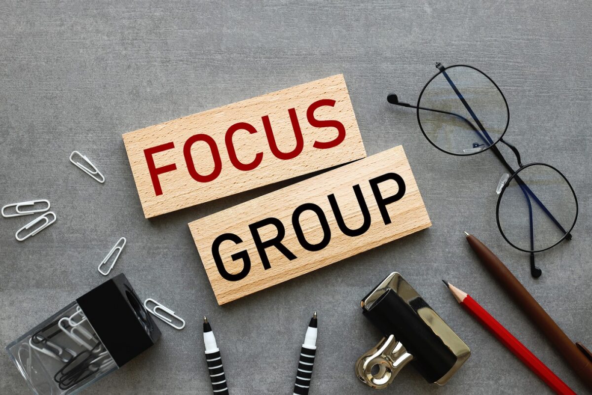 Two wooden blocks on a grey surface, one with FOCUS in red letters, the other with GROUP in black letters.