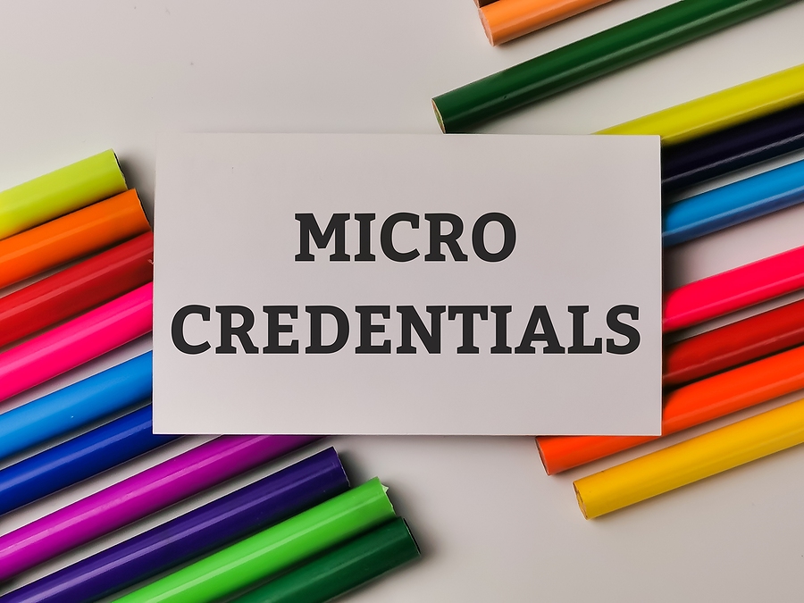 A white card with the words MICRO CREDENTIALS in black, surrounded by colourful pencils.