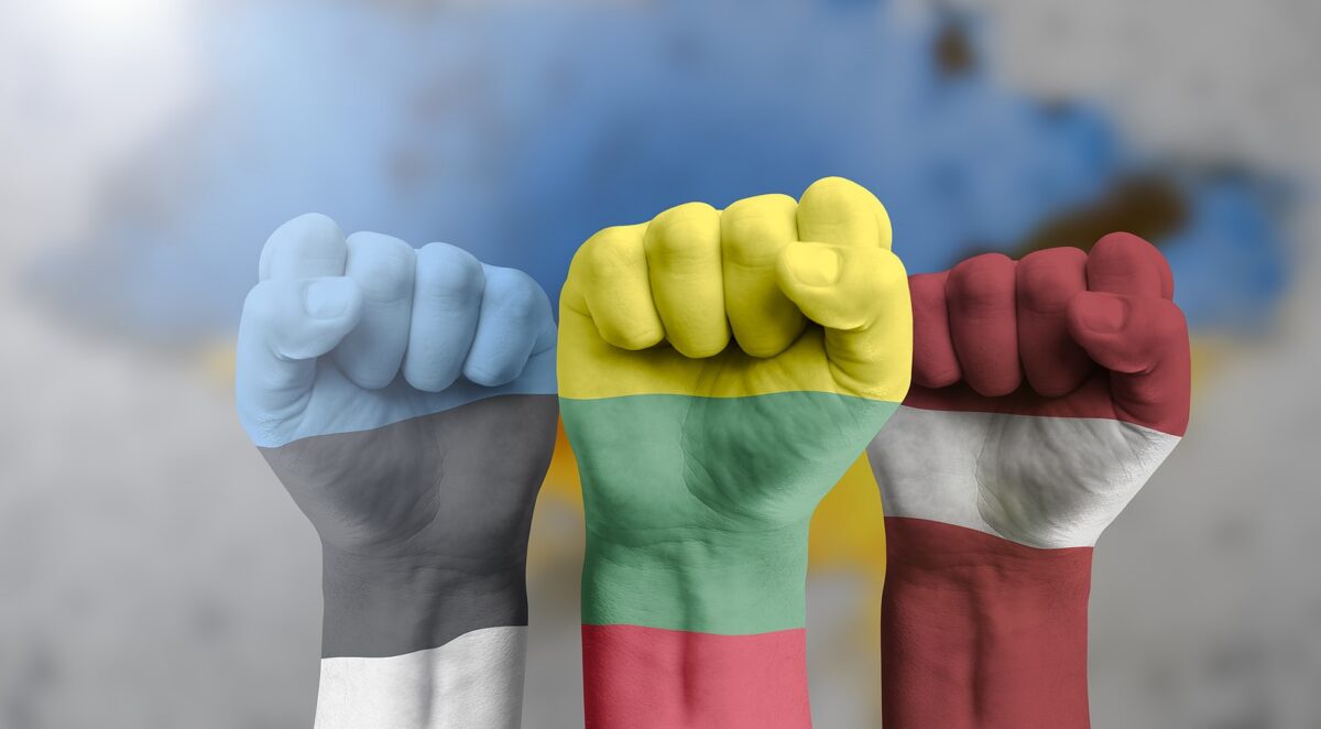 Three fists, painted with the flags of Estonia, Lithuania, and Latvia, raised against a blurred background.