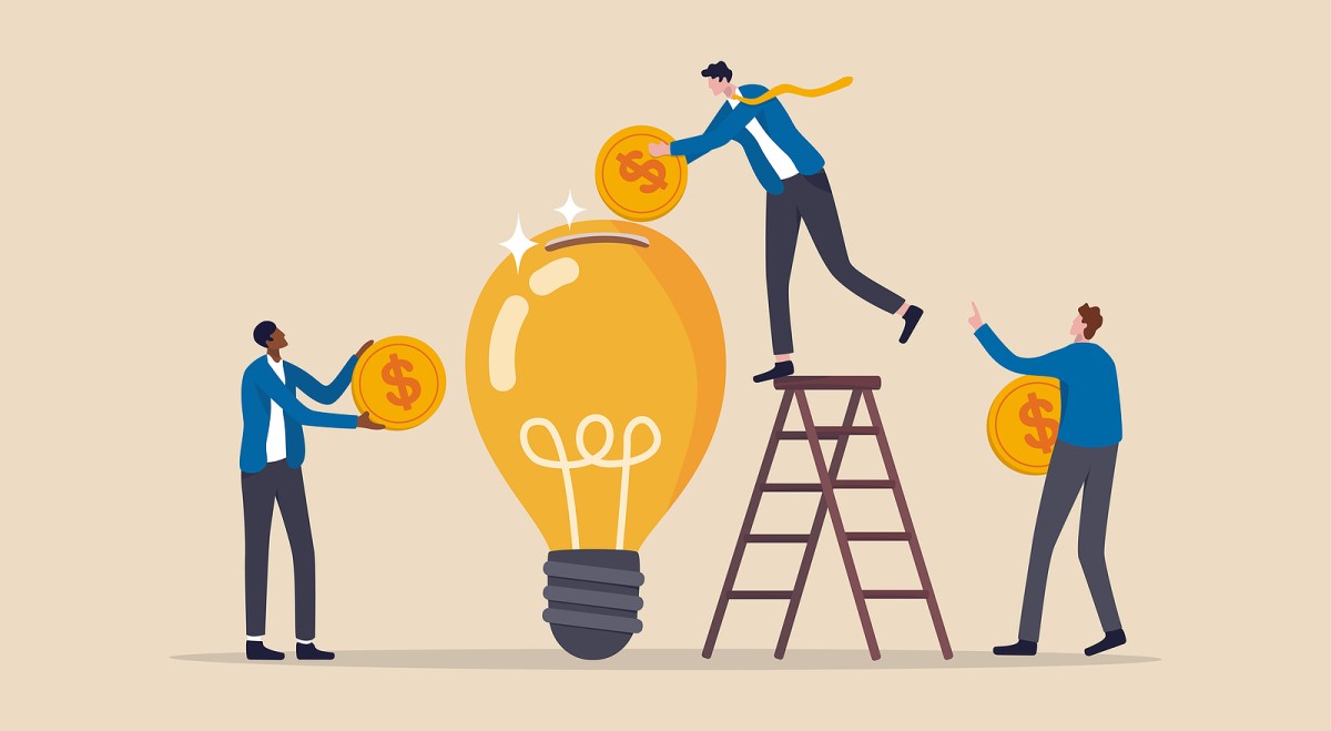 Three people putting large gold coins with dollar signs into a giant lightbulb acting as a piggy bank.