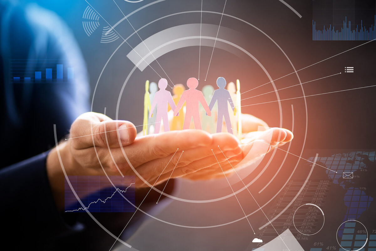 Hands holding a circle of diverse paper cut-out people, surrounded by digital data visualisations.