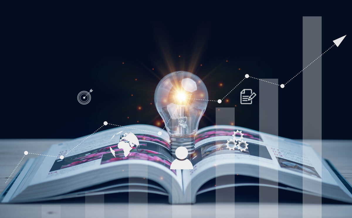 An open book with a glowing light bulb on its pages, surrounded by digital icons and a rising bar chart.