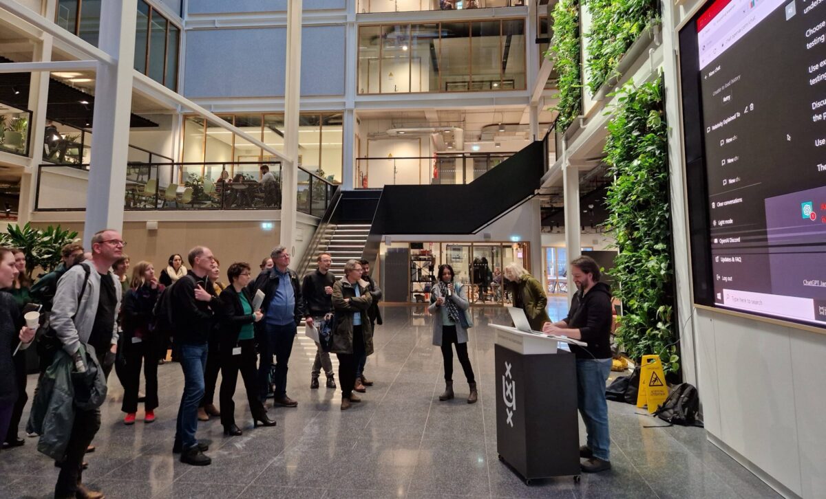 A group of people attending a ChatGPT workshop, looking at a large screen displaying the ChatGPT interface.