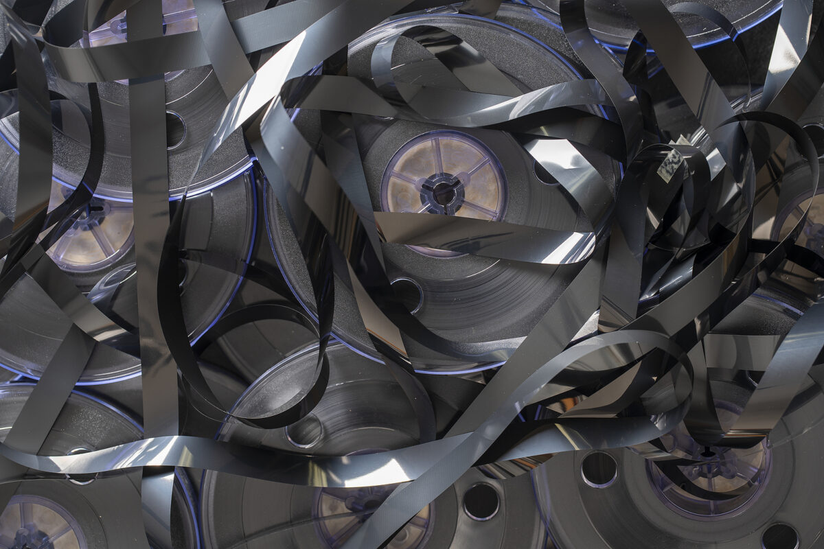 A tangled mess of black magnetic tape spilling out of several vintage video reels.