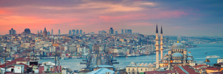 Panoramic view of Istanbul at sunset, showing the Bosphorus, mosques, and city skyline.