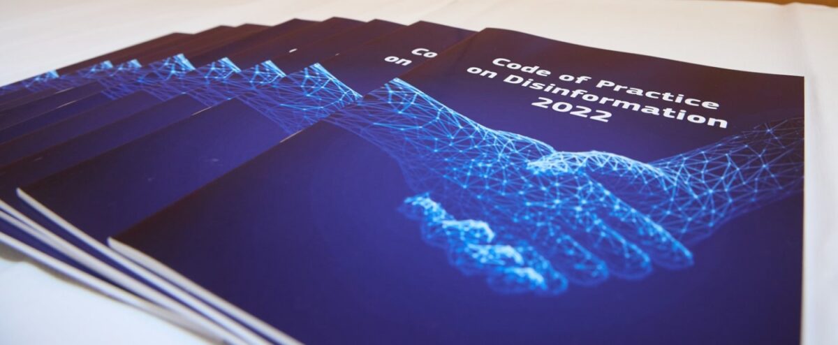 Stack of dark blue booklets titled Code of Practice on Disinformation 2022, featuring a digital handshake graphic