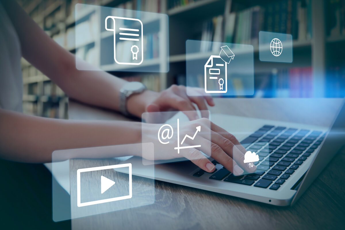 Person typing on a laptop with various digital icons floating above, including a diploma, globe, and cloud.