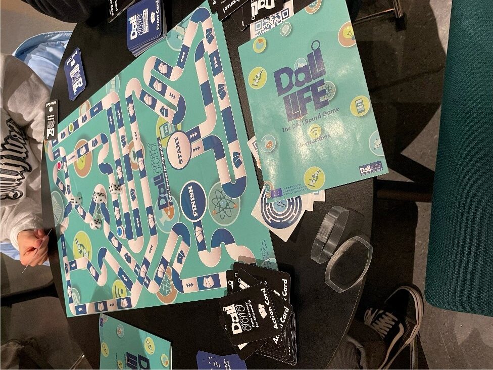 A board game called Dali Life, with dice on the board, and cards and instructions next to it.