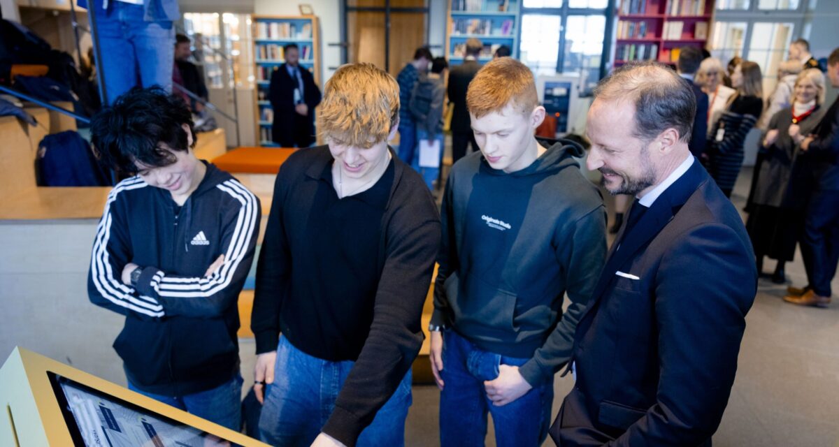 Four men, three young, one older, looking at and interacting with a digital display screen.