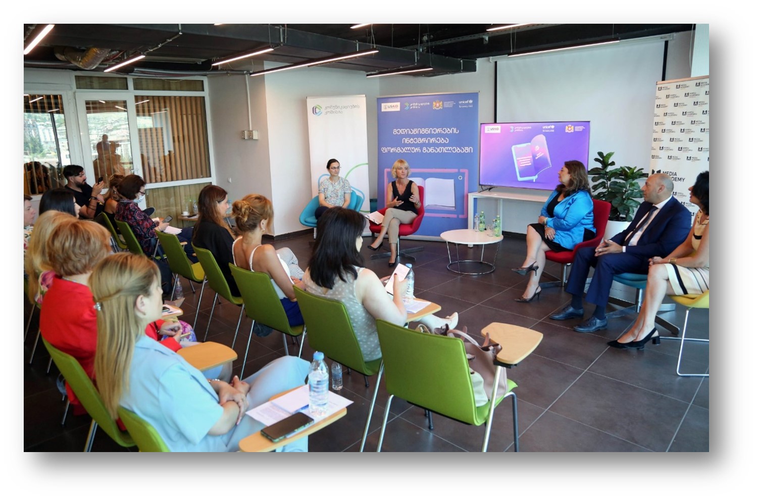 Audience seated in a room, facing a panel of four speakers at a media literacy event in Georgia.