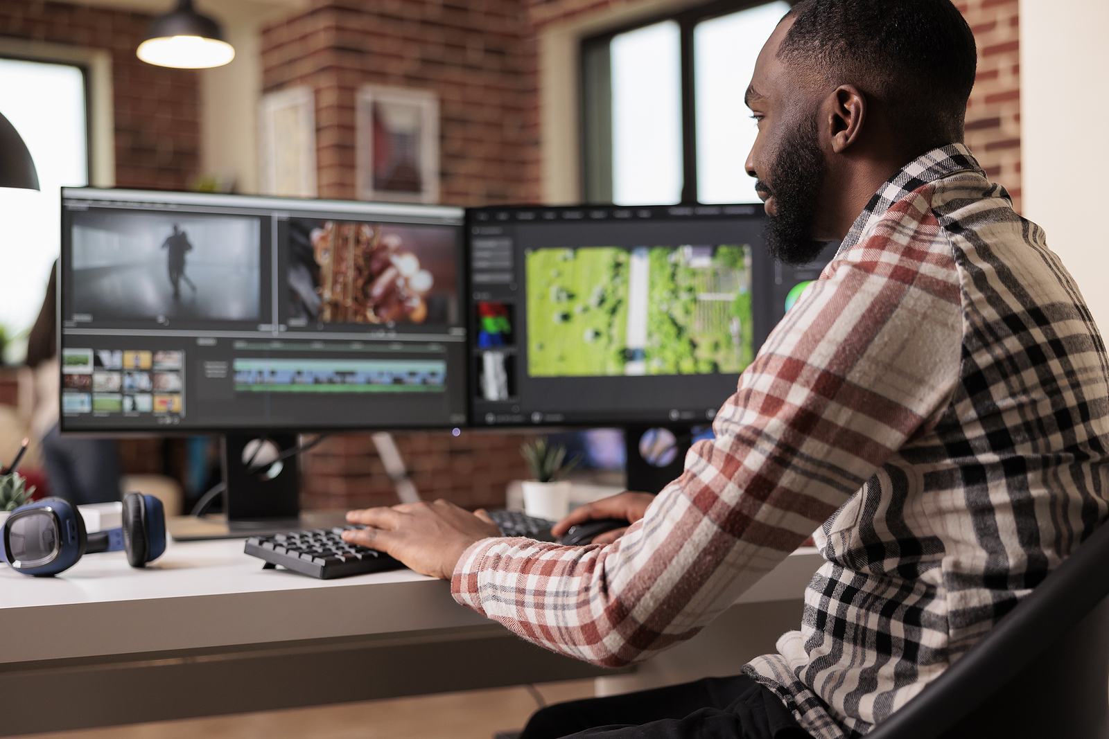 Man editing video on two computer monitors, with headphones on the desk