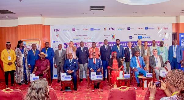 Group photo of 25 people, mostly men in suits, some women, at a conference in front of a banner.